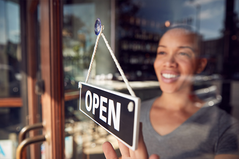 woman hanging open sign on business window